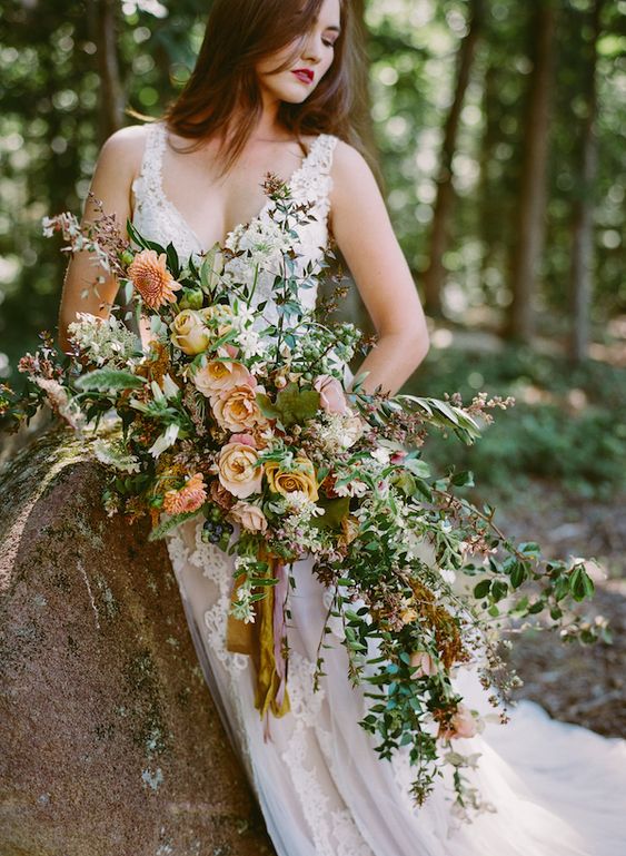 A fab oversized wedding bouquet of peachy and rust colored blooms, greenery, white fillers and various foliage for the fall
