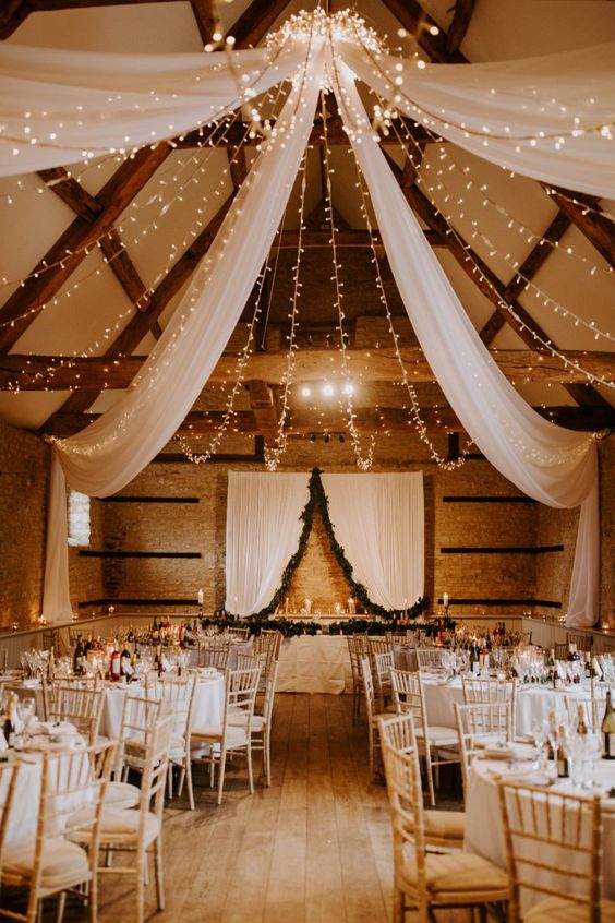 a gorgeous canopy of neutral fabric and lights plus candles on the tables will illuminate the wedding venue in a very cool way