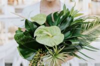 a green tropical wedding bouquet with succulents, air plants and large monstera leaves for a modern bride