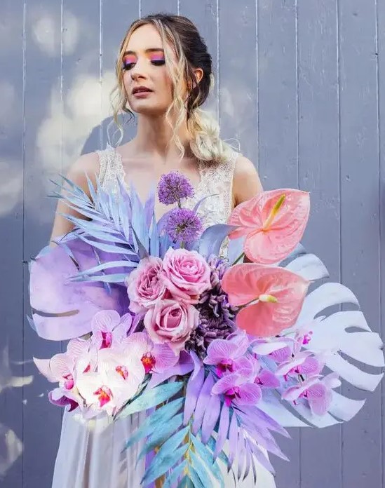 A jaw dropping iridescent wedding bouquet with colorful fronds, blooms and leaves, in purple, pink and blue is amazing