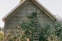a jaw-dropping outdoor barn wedding ceremony space all covered with greenery and pink blooms is a chic idea to go for