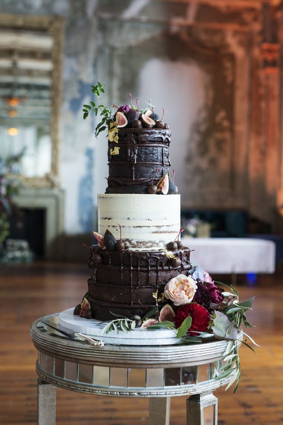 a lovely and delicious naked white and chocolate wedding cake with chocolate drip, fresh fruit and berries and bold blooms for a decadent wedding