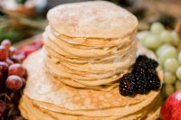 a lovely and simple crepe wedding cake with cream and blackberries and lots of fresh fruit and berries around for a boho fall wedding