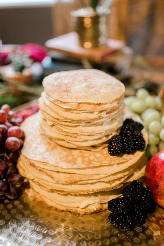 a lovely and simple crepe wedding cake with cream and blackberries and lots of fresh fruit and berries around for a boho fall wedding
