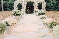 a luxurious wedding ceremony space with a lush white floral arch, a white petal pattern on the floor, white floral arrangements