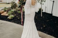 a mermaid boho lace wedding dress with a train, a cutout back and bell sleeves for a boho barn bride