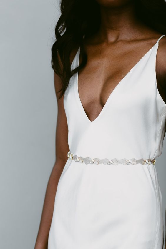a minimalist slip wedding dress with a plunging neckline and a lovel mother of pearl sash are a lovely combo for a modern bride