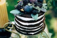 a naked chocolate wedding cake topped with fresh fruit and berries, with greenery is a fantastic and yummy-looking idea for a fall wedding