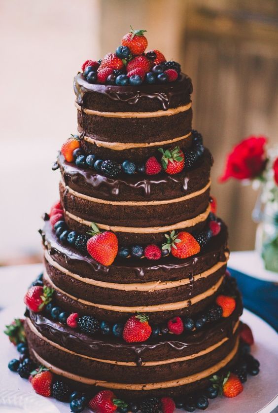 a naked chocolate wedding cake with chocolate drip and fresh berries is a yummy and cool idea for a rustic or relaxed wedding
