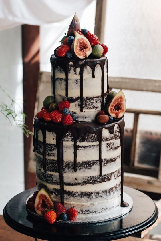 a naked chocolate wedding cake with chocolate drip, fresh fruit and berries is a fantastic idea for a rustic or a boho wedding
