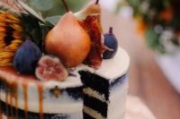 a naked chocolate wedding cake with fresh fruit and berries on top, greenery, a sunflower and caramel drip is a gorgeous idea for a fall boho wedding