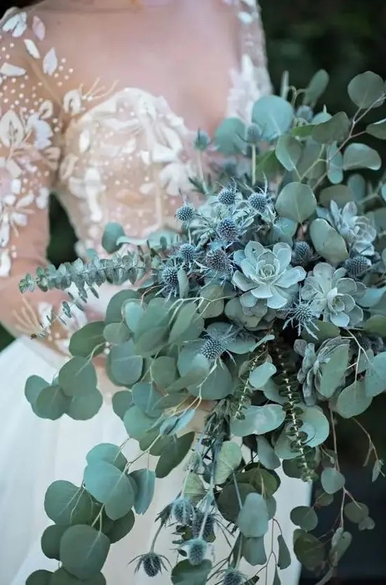 A pale green cascading wedding bouquet with eucalyptus, succulents and blue thistles for a fairy tale feel