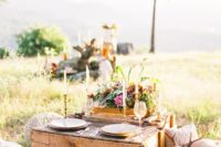 a pallet table, thin candles, bright blooms and greenery, blankets and pillows for a cozy summer picnic wedding