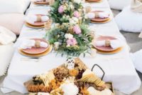 a pastel beach wedding picnic with a low table, pastel flowers and greenery, pastel plates and woven lanterns
