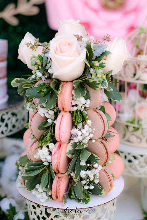 a refined macaron tower with greenery, baby's breath and pink roses on top is a lovely alternative to a usual cake