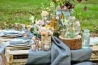 a rustic wedding picnic with a pallet table, a blue runner, pastel and neutral blooms, greenery, tree stumps and wood slices