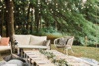 a simple and cute casual wedding picnic with a low table, printed blankets and pillows and a greenery runner plus candles