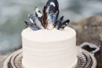 a simple white beach bridal shower cake with mussel shells on top is stylish and elegant