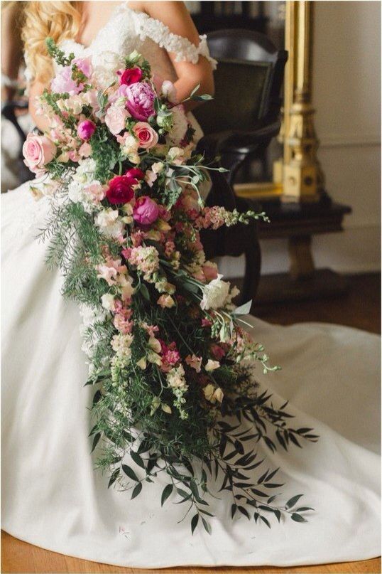a super lush cascading wedding bouquet of greenery, white, pink, hot pink and burgundy blooms is a bold and catchy idea