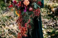 a super lush cascading wedding bouquet with lots of greenery, red leaves, berries and blooms of various shades