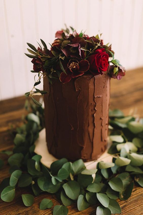 a tall chocolate wedding cake topped with purple and burgundy blooms and greenery is a gorgeous idea for a fall wedding
