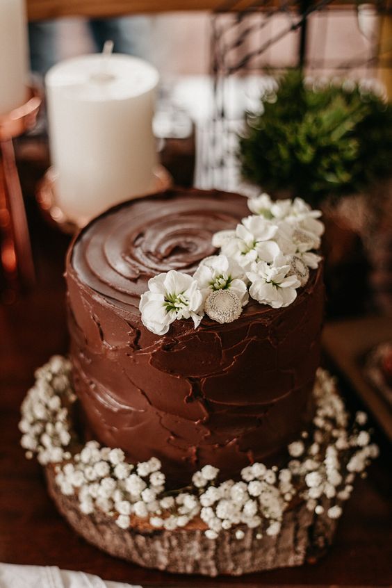 a textural chocolate wedding cake topped with white blooms and with baby's breath at the bottom is amazing for any relaxed wedding