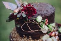 a textural chocolate wedding cake with neutral and bright blooms, berries, twigs and nuts is a lovely idea for a fall wedding