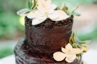 a textural chocolate wedding cake with white blooms and greenery is a stylish and bold idea for a modern wedding, it looks delicious