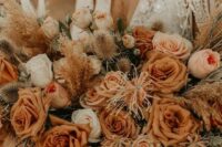 a warm-colored rust wedding bouquet with white blooms, dried touches and greenery for a desert boho bride