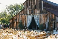 a welcoming outdoor barn wedding reception with round tables and stained chairs, string lights and bold blooms is a cool space