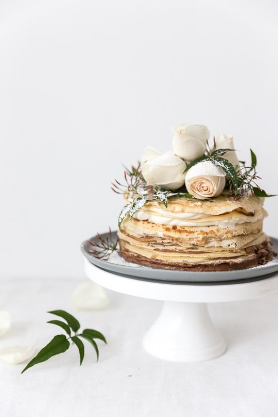an adorable crepe wedding cake with cream cheese, white blooms, greenery and sugar powder is a lovely wedding dessert
