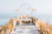 an airy wedding ceremony space with a clear backdrop with grass, pampas grass lining up the aisle and the backdrop