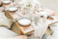 an ethereal pastel beach bridal picnic with pink and grey textiles, neutral candles and blooms and green glasses