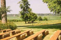 an outdoor barn wedding ceremony space with benches built of hay and wooden planks is a very cool idea to try