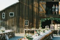 an outdoor barn wedding reception space with long tables, neutral linens, pink florals and greenery and stained chairs