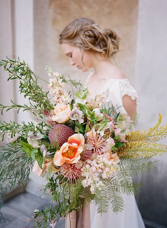 an oversized pastel wedding bouquet of peachy and blush blooms, lots of textural and dimensional greenery and foliage for a spring bride