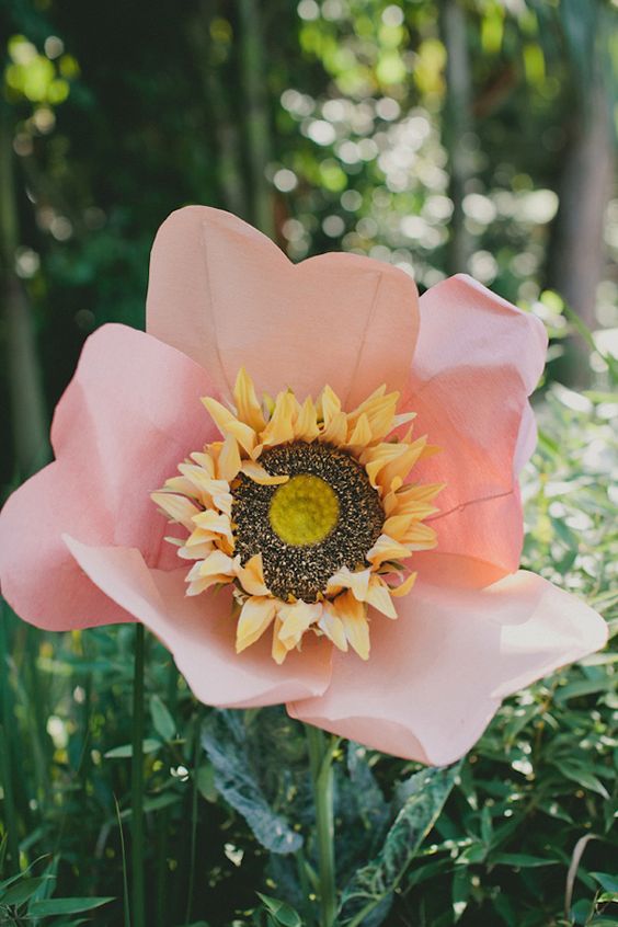 an oversized pink paper bloom with a sunflower inside is a fun and cool decor idea that you can realize yourself