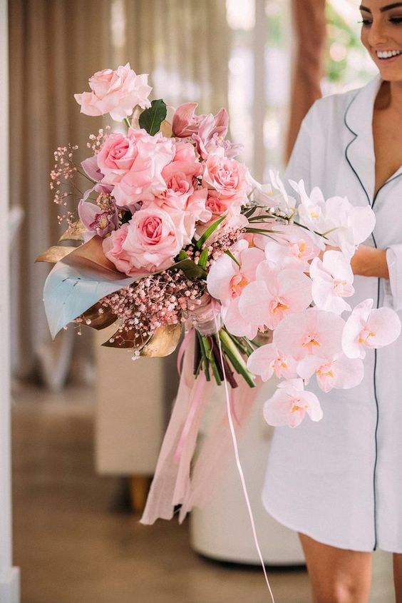 an oversized pink wedding bouquet with roses, orchids, baby's breath, foliage is amazing for spring and summer brides