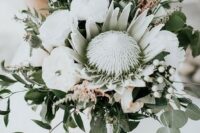 an oversized wedding bouquet of a king protea, white peonies, berries, thistles and greenery for a bold statement