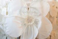 an oversized white bloom to decorate a wedding arch is a lovely alternative to usual wedding flowers or signs