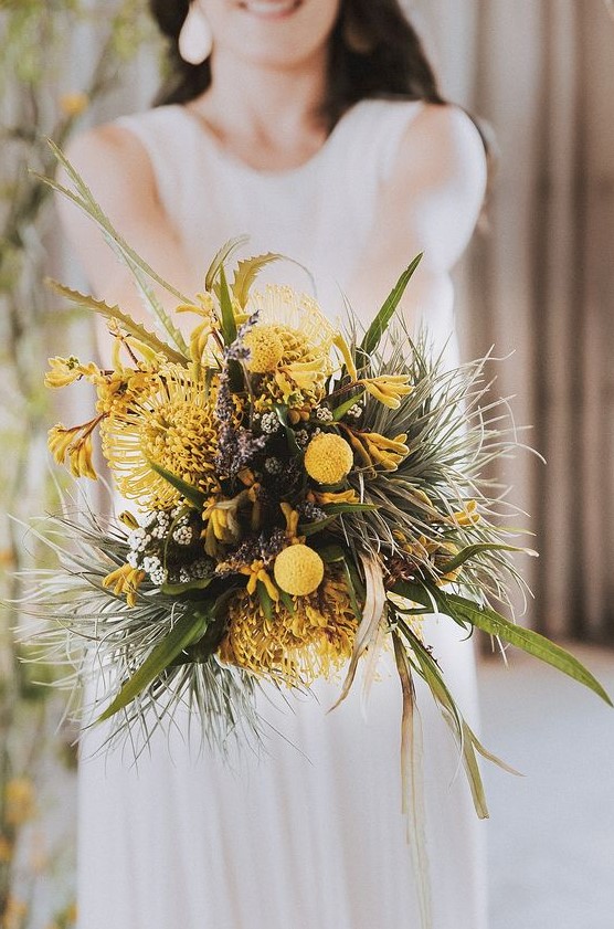 an unusual wedding bouquet of various greenery, yellow blooms and billy balls, astilbe looks textural and very pretty