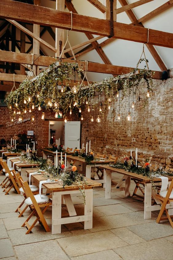 lovely lighting pieces of wooden ladders, greenery and Edison bulbs hanging down and tall and thin candles on the table