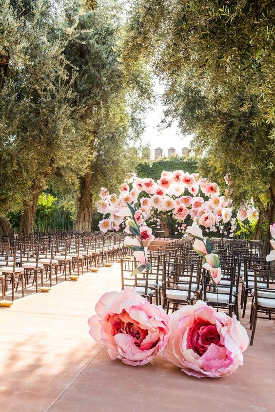 oversized pink paper blooms for styling a wedding backdrop and wedding aisle are a very eco friendly idea to try