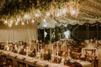 string lights and Edison bulbs hanging over the venue and candles on the tables illuminate the space in a gorgeous way