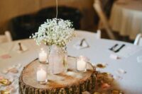 a barn wedding centerpiece of a wood slice, petals, candles and baby’s breath in a jar plus a chalkboard table number