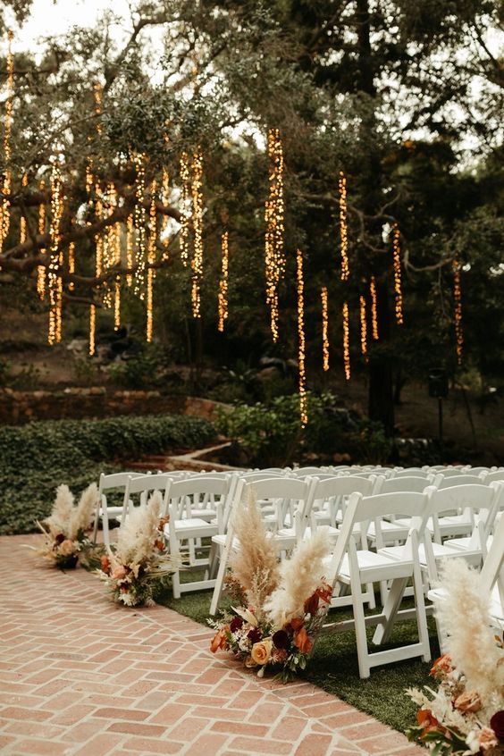 a beautiful boho fall wedding aisle with neutral, burgundy and rust blooms and pampas grass plus greenery