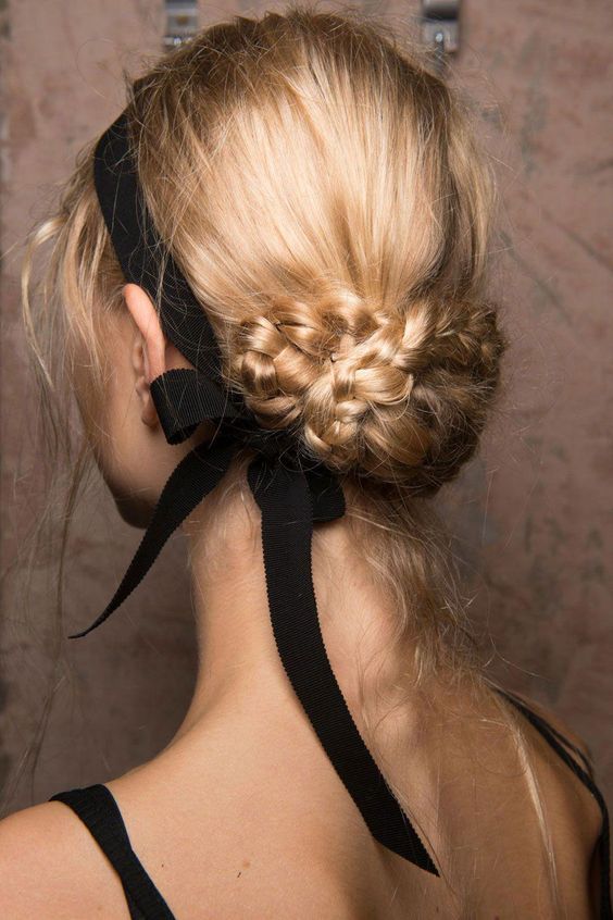 a beautiful braided low updo with a volume on top and a black ribbon bow for a super elegant and girlish look