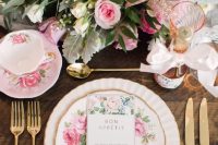 a beautiful vintage bridal shower table setting with pink and blush blooms and greenery, floral porcelain and gold cutlery is chic