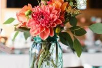 a blue mason jar with a colorful floral arrangement for a rustic fall wedding