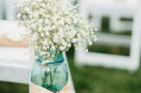 a blue mason jar with blush ribbon and baby’s breath for a rustic summer aisle